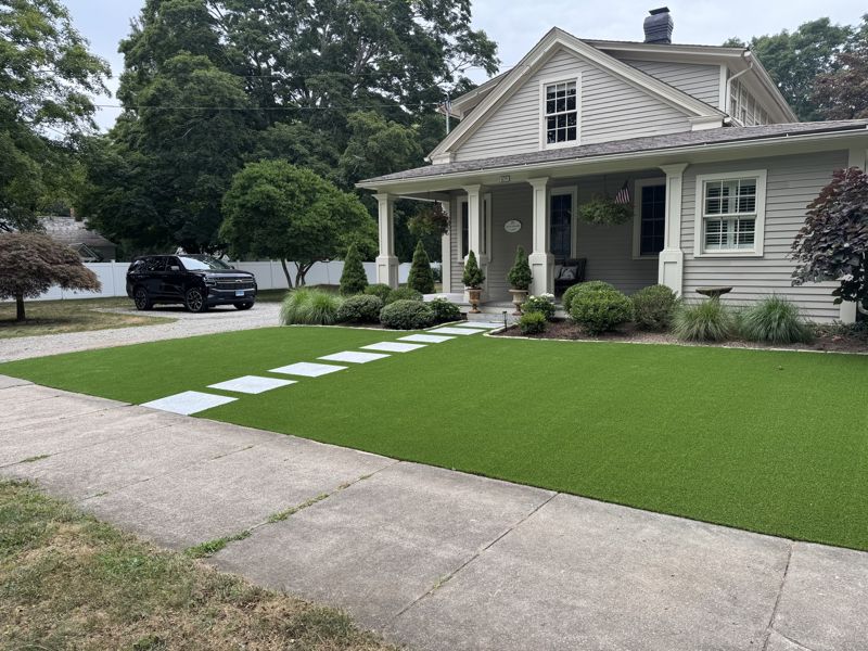 Synthetic lawn and a curved path leading to a Craftsman-style home