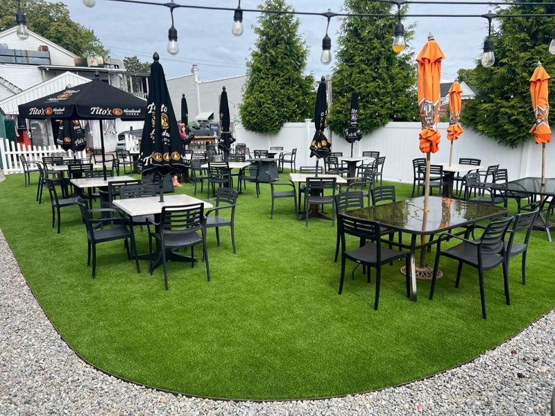 Outdoor restaurant seating arranged around a synthetic-turf patio